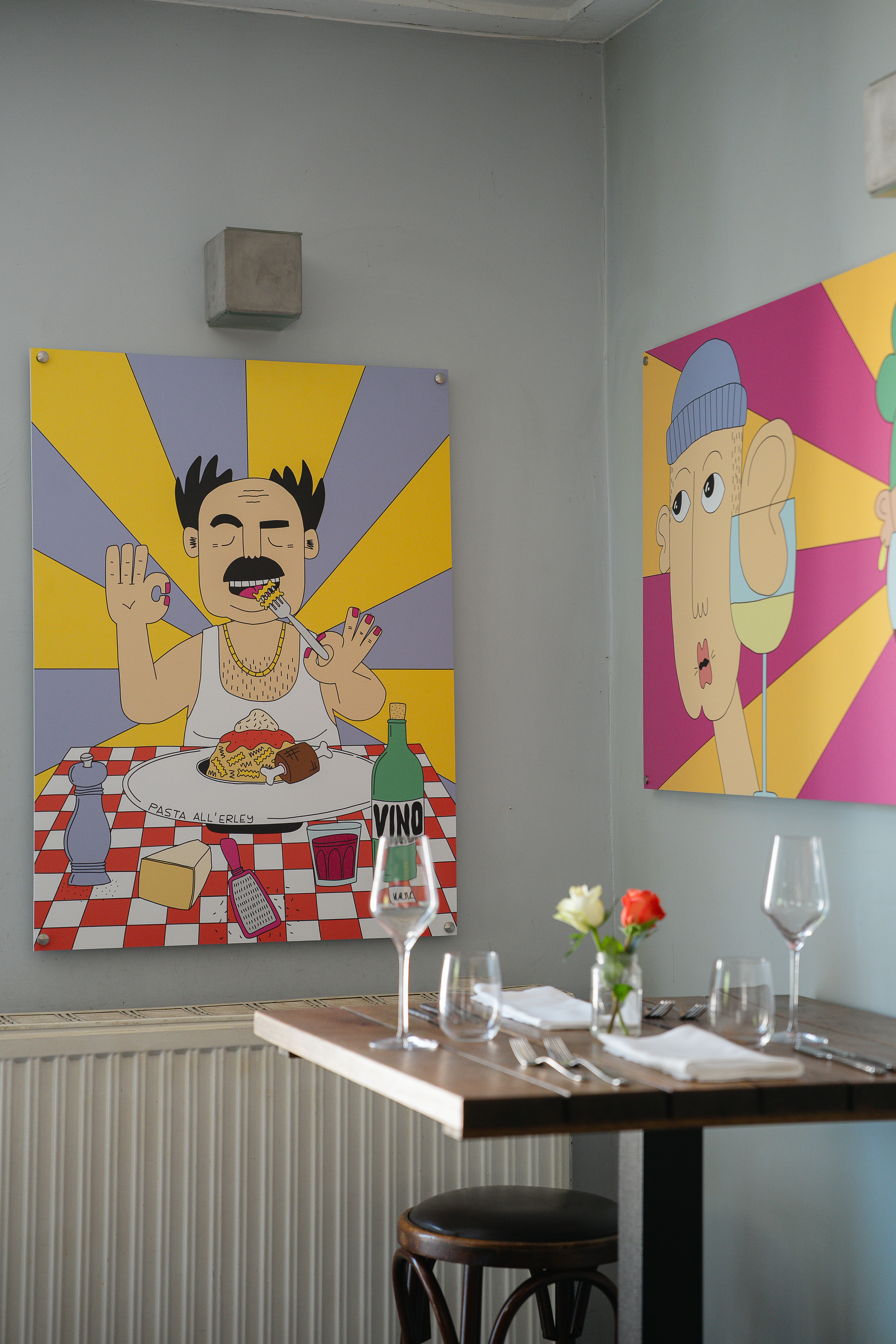 Ein gedeckter Tisch inmitten eines kreativen Spektakels: Im Restaurant Allerley prangen zwei kunstvoll gestaltete Bilder an der Wand, deren Farbigkeit den Raum zu erfüllen scheint. Hier verschmelzen Kulinarik und Kunst zu einem harmonischen Ganzen.