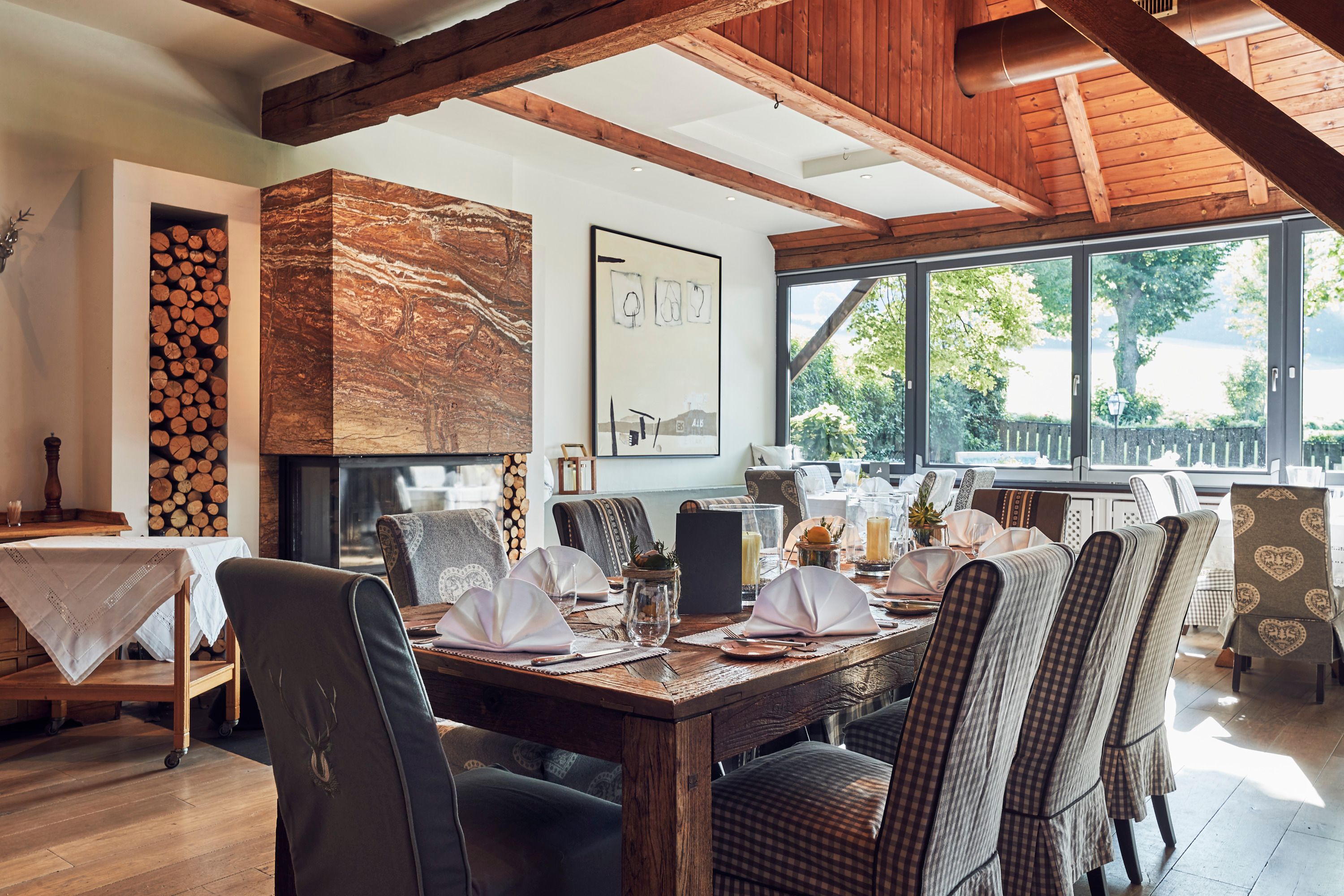 Elegantes Restaurant mit Holzbalken, Kamin und gedeckten Tischen.