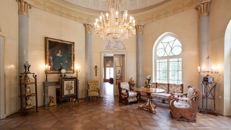 Eleganter Raum im Geymüllerschlössel mit Kronleuchter, antiken Möbeln und Gemälde.