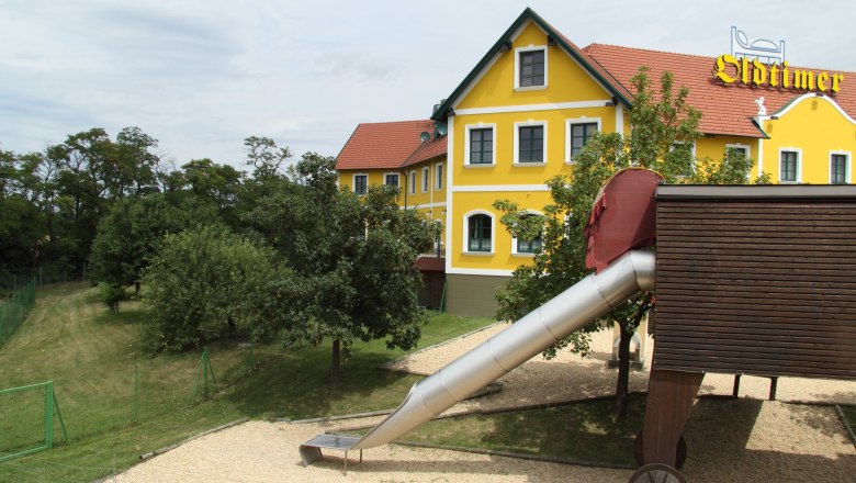 Gelbes Gebäude mit rotem Dach und Rutsche im Vordergrund.