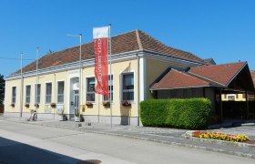 Gemeindeamt in Rauchenwarth, gelbes Gebäude mit rotem Dach und Blumen.