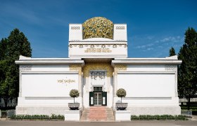 Front view of the Secession building in Vienna with golden dome and inscription.