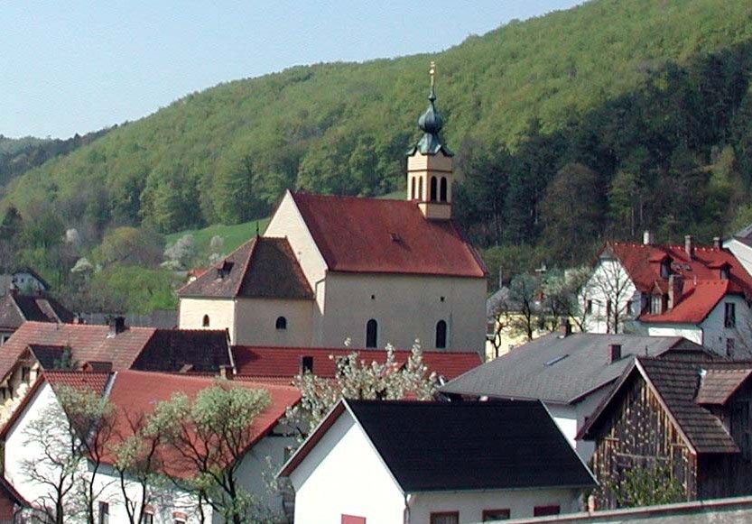 Wallfahrtskirche Maria Raisenmarkt in einer ländlichen Umgebung mit Hügeln im Hintergrund.