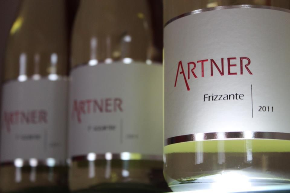 Nahaufnahme von Weinflaschen mit dem Etikett 'Artner Frizzante 2011'.