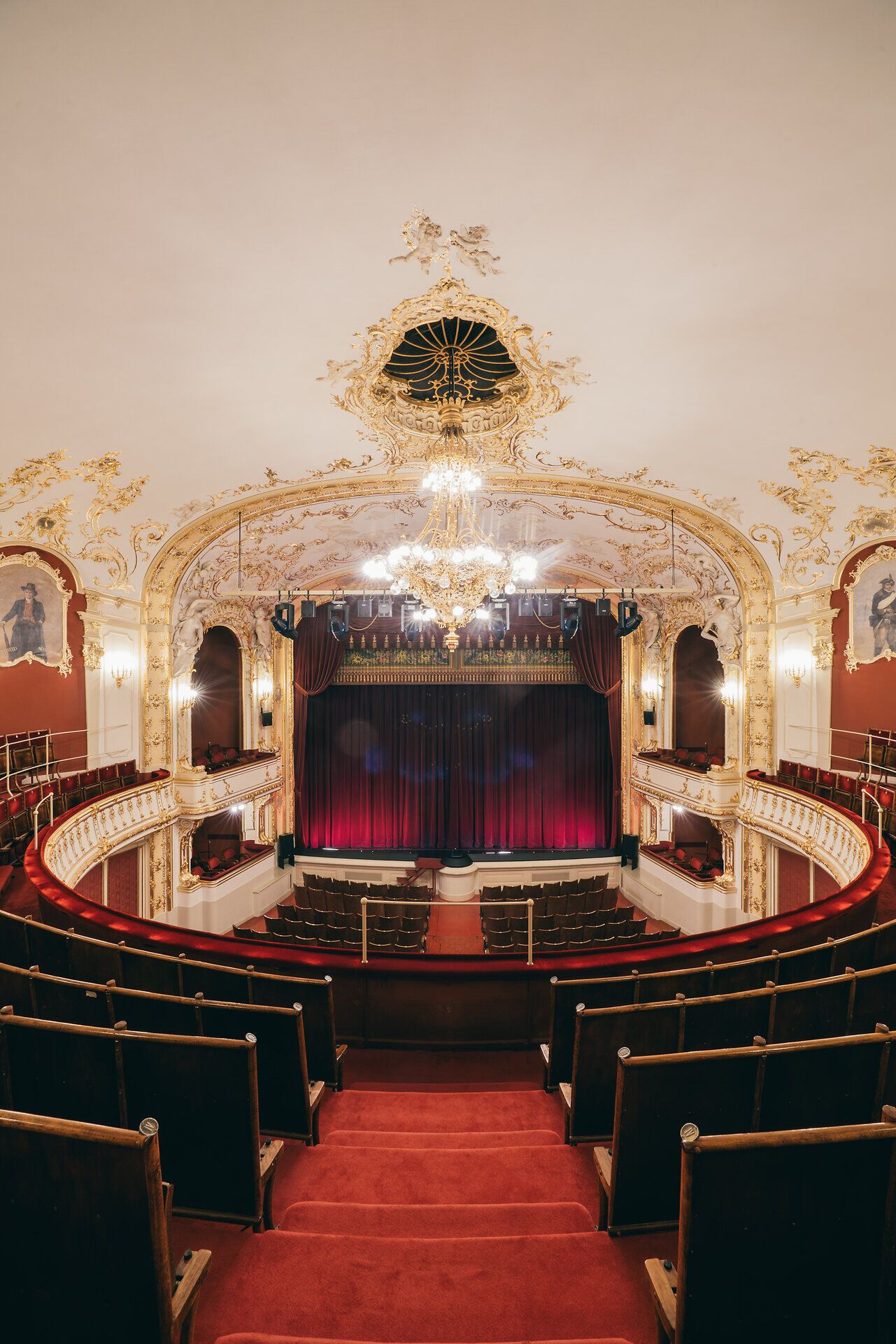 Das Stadttheater Berndorf strahlt eine elegante Atmosphäre aus, die die Vorfreude auf unvergessliche Aufführungen weckt. Die kunstvoll gestaltete Decke und die opulente Beleuchtung verleihen dem Raum einen Hauch von Magie, während die roten Samtvorhänge auf den großen Moment warten. Hier wird Kultur lebendig und lädt Besucher ein, in die Welt des Theaters einzutauchen.