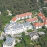 Aerial view of a residential complex with red roofs, surrounded by trees.