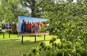 Outdoor-Fotoausstellung mit Bildern von Menschen in traditioneller Kleidung auf einer Wiese.
