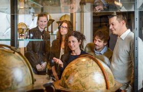 Gruppe von Menschen betrachtet antike Globen in einem Museum.