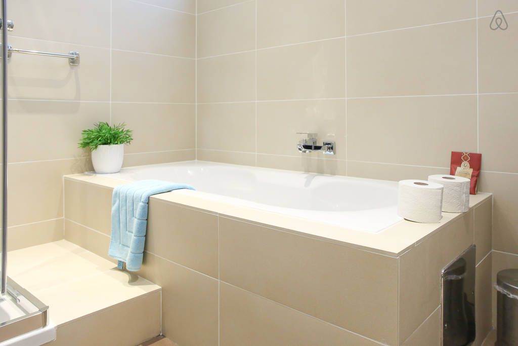 Modernes Badezimmer mit Badewanne, Handtuch, Pflanze und Toilettenpapier.