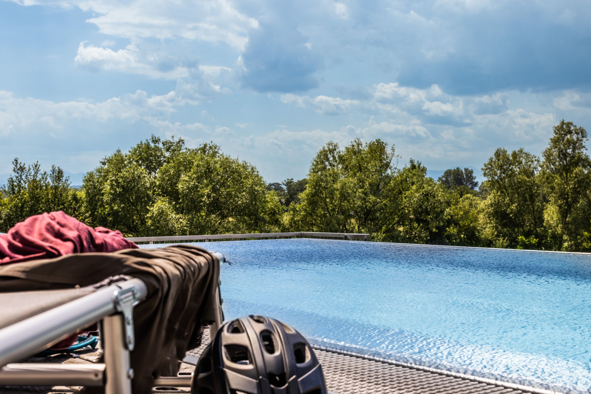 Ein Infinity-Pool mit Bäumen im Hintergrund und einem Fahrradhelm im Vordergrund.