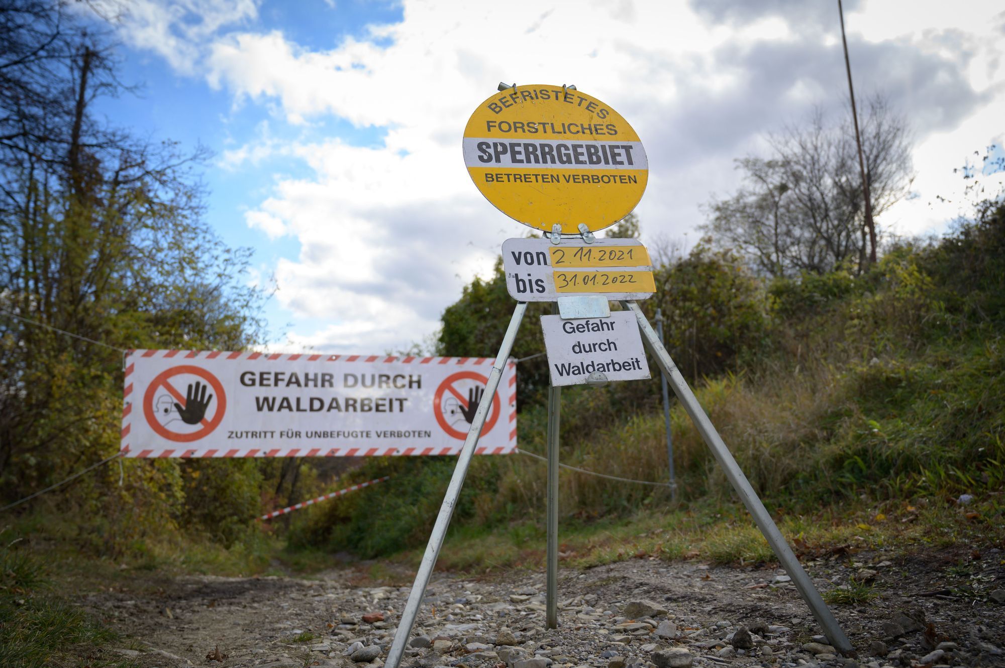 Sperrschilder vor einer gesperrten Mountainbike Strecke. Gefahr durch Waldarbeit und Befristetes forstliches Sperrgebiet.