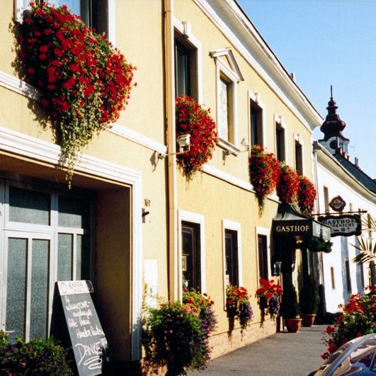 Ein traditionelles Gasthaus mit gelber Fassade und roten Blumen an den Fenstern.