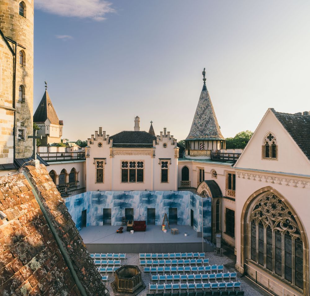 In der malerischen Kulisse des Festivallands entfaltet sich eine zauberhafte Atmosphäre, während die Stühle auf dem Platz auf die kommenden Darbietungen warten. Die historischen Gebäude umrahmen die Bühne und laden Besucher ein, in eine Welt voller Kunst und Kultur einzutauchen.