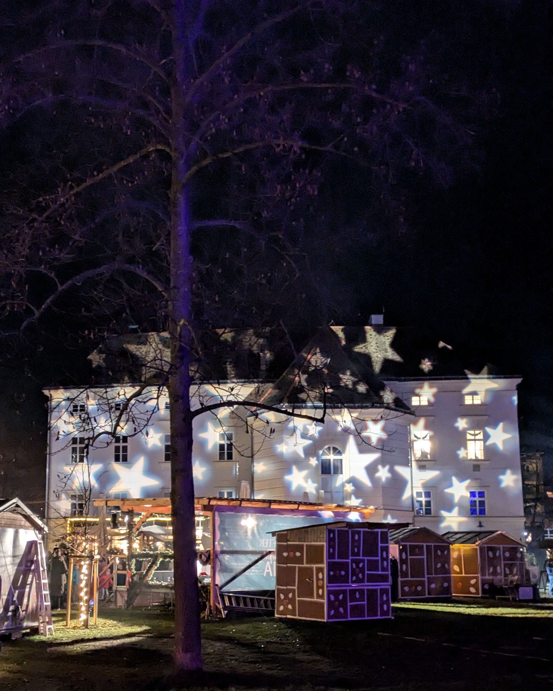 Das Rathaus in Bad Vöslau bei Dunkelheit im Advent. Hell leuchtende Sterne sind projiziert auf das Rathaus.