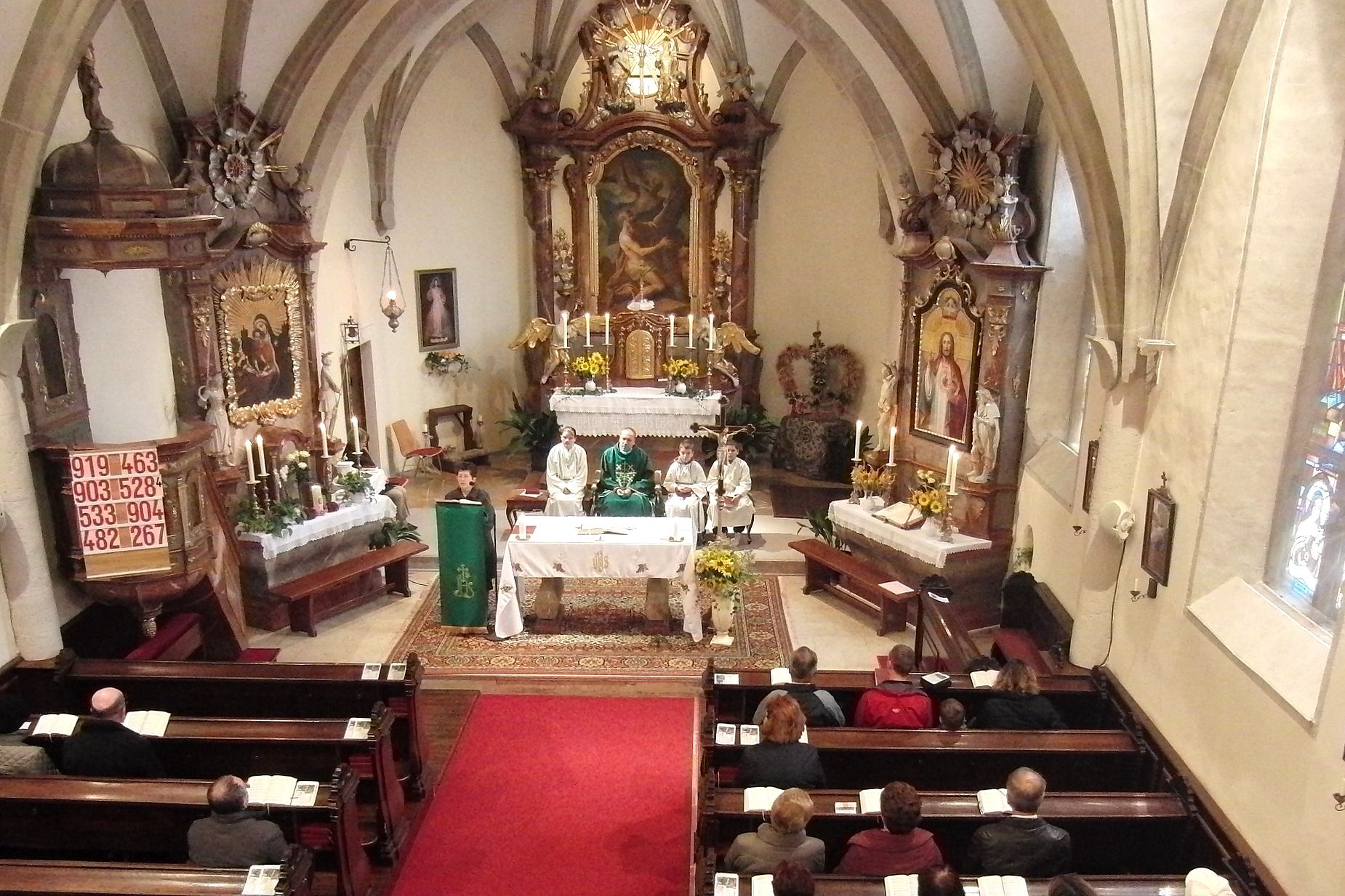 Innenansicht einer Kirche während einer Messe mit Geistlichen und Gläubigen.