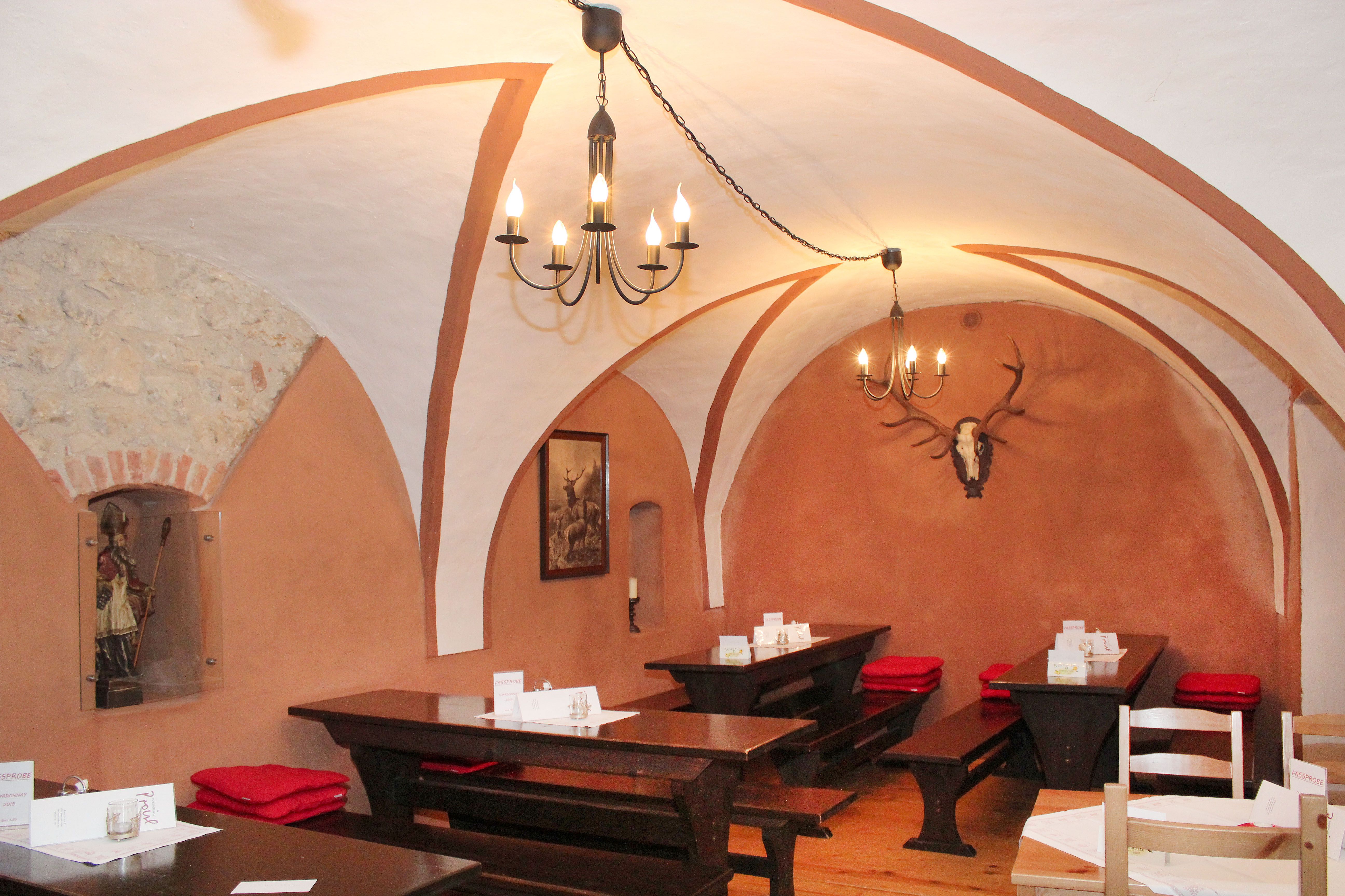 Rustikales Restaurant mit Gewölbedecke, Holztischen und Hirschgeweih an der Wand.