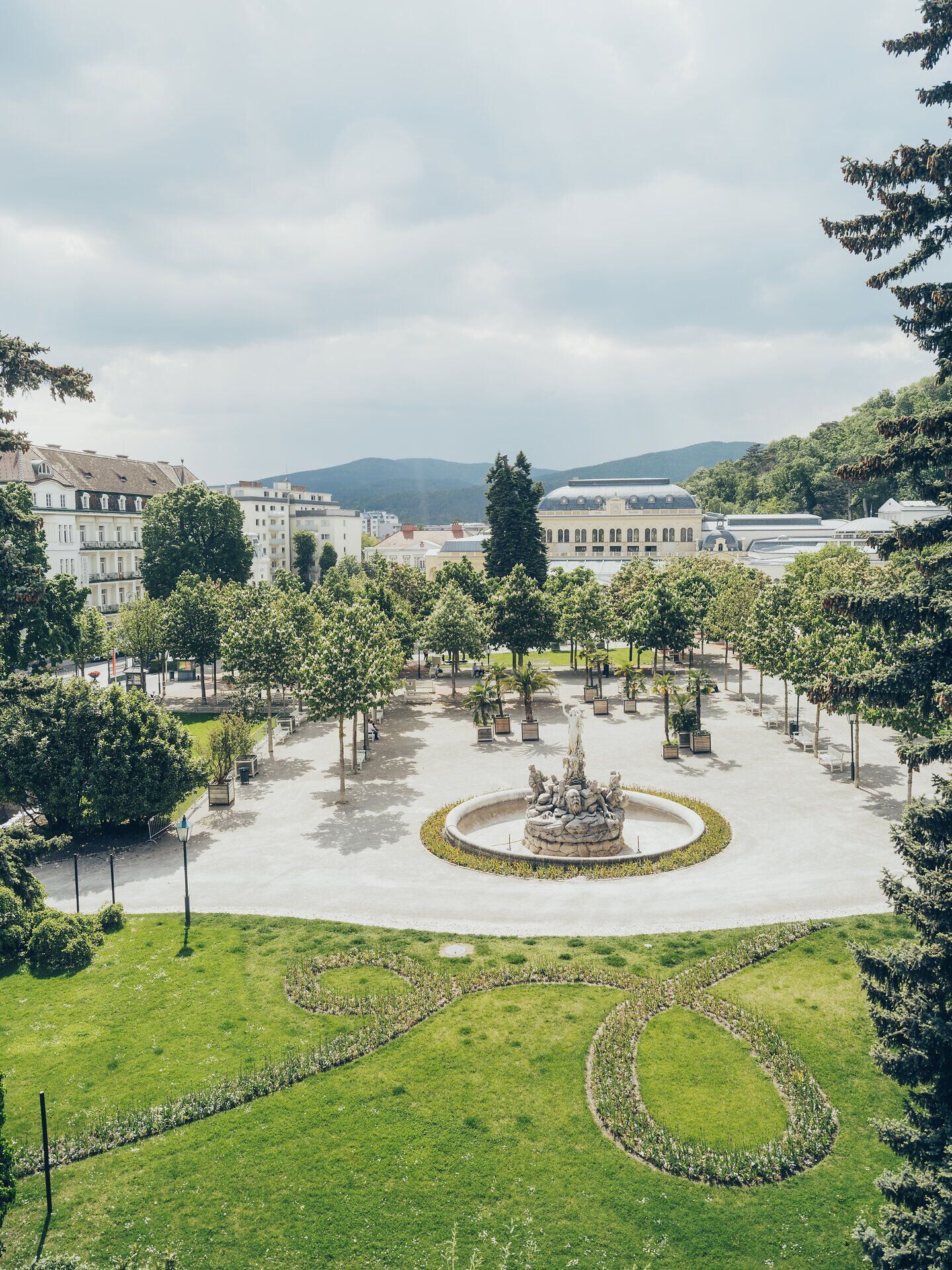 Der Kurpark lädt mit seinen gepflegten Grünflächen und schattenspendenden Bäumen zu einem entspannenden Spaziergang ein. Die sanfte Brise und das Plätschern des Brunnens schaffen eine harmonische Atmosphäre, die zum Verweilen einlädt.