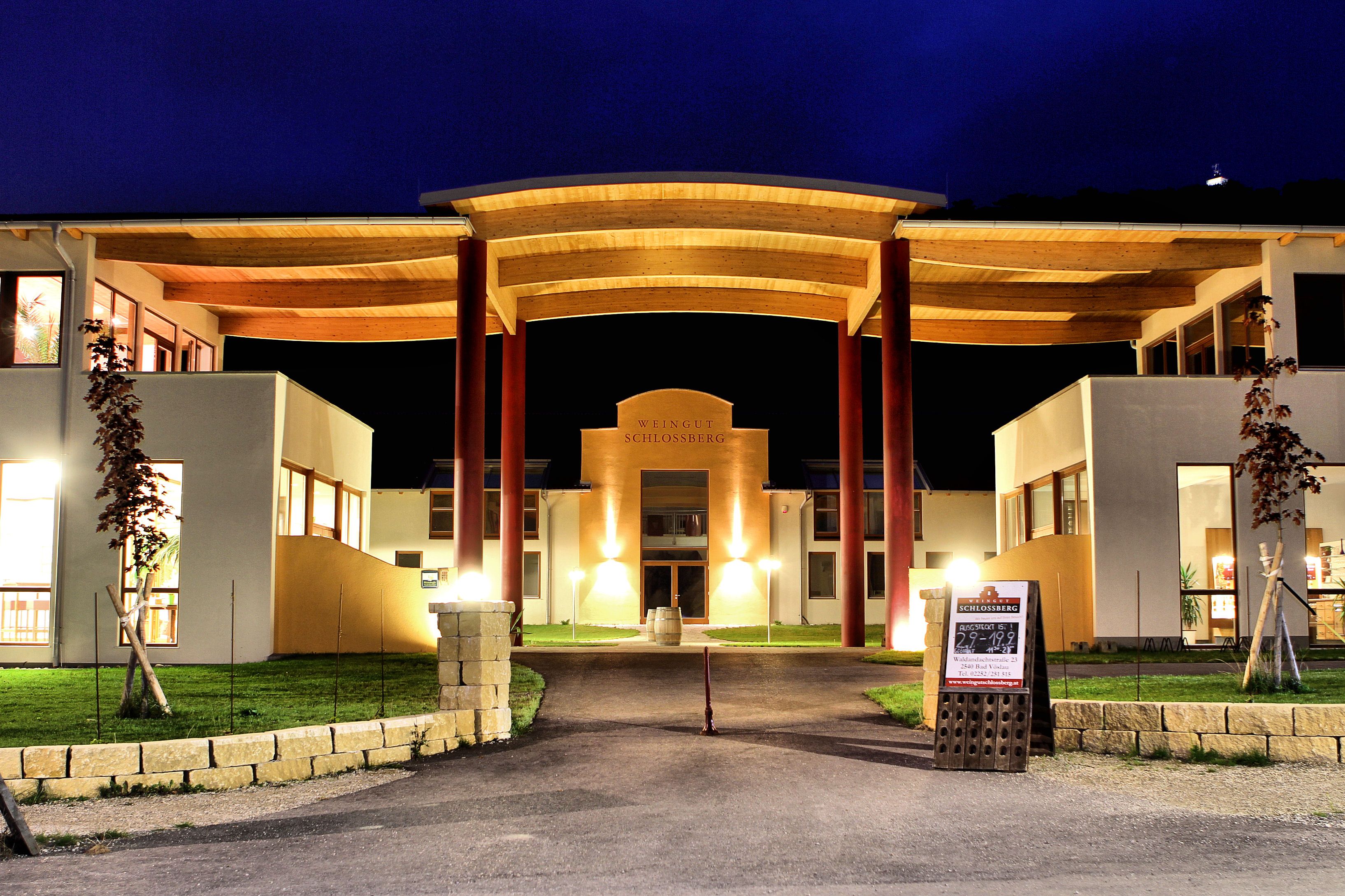 Beleuchtetes Gebäude des Weinguts Schlossberg bei Nacht.