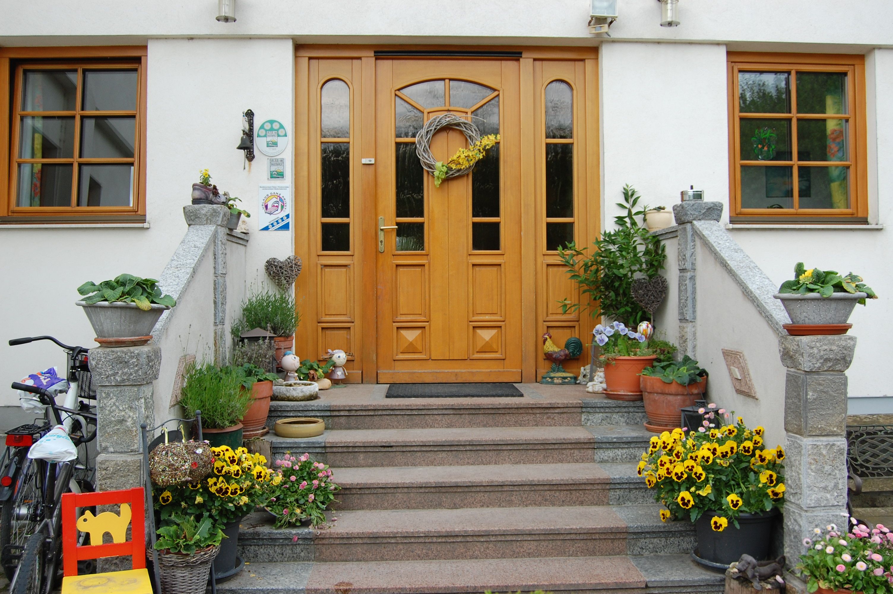 Vorderseite eines Hauses mit Holztür, Treppe und Blumendekoration.