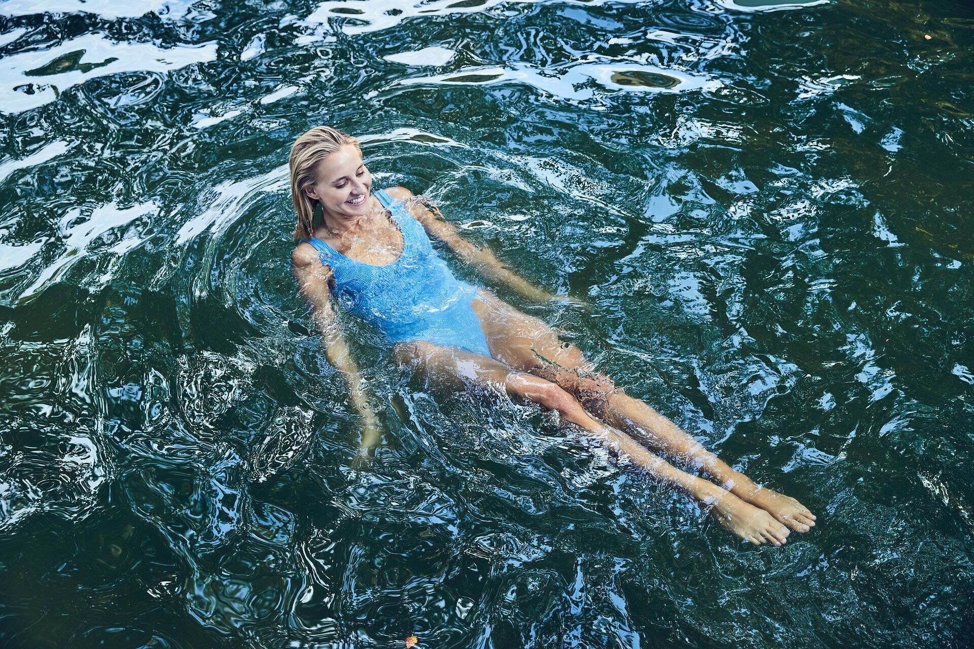 Im erfrischenden Wasser des Freibads gleitet eine entspannte Person sanft dahin, während die warmen Sonnenstrahlen auf die Haut scheinen. Umgeben von üppigem Grün und der ruhigen Atmosphäre des Sommers, lädt dieser Ort zum Verweilen und Genießen ein.
