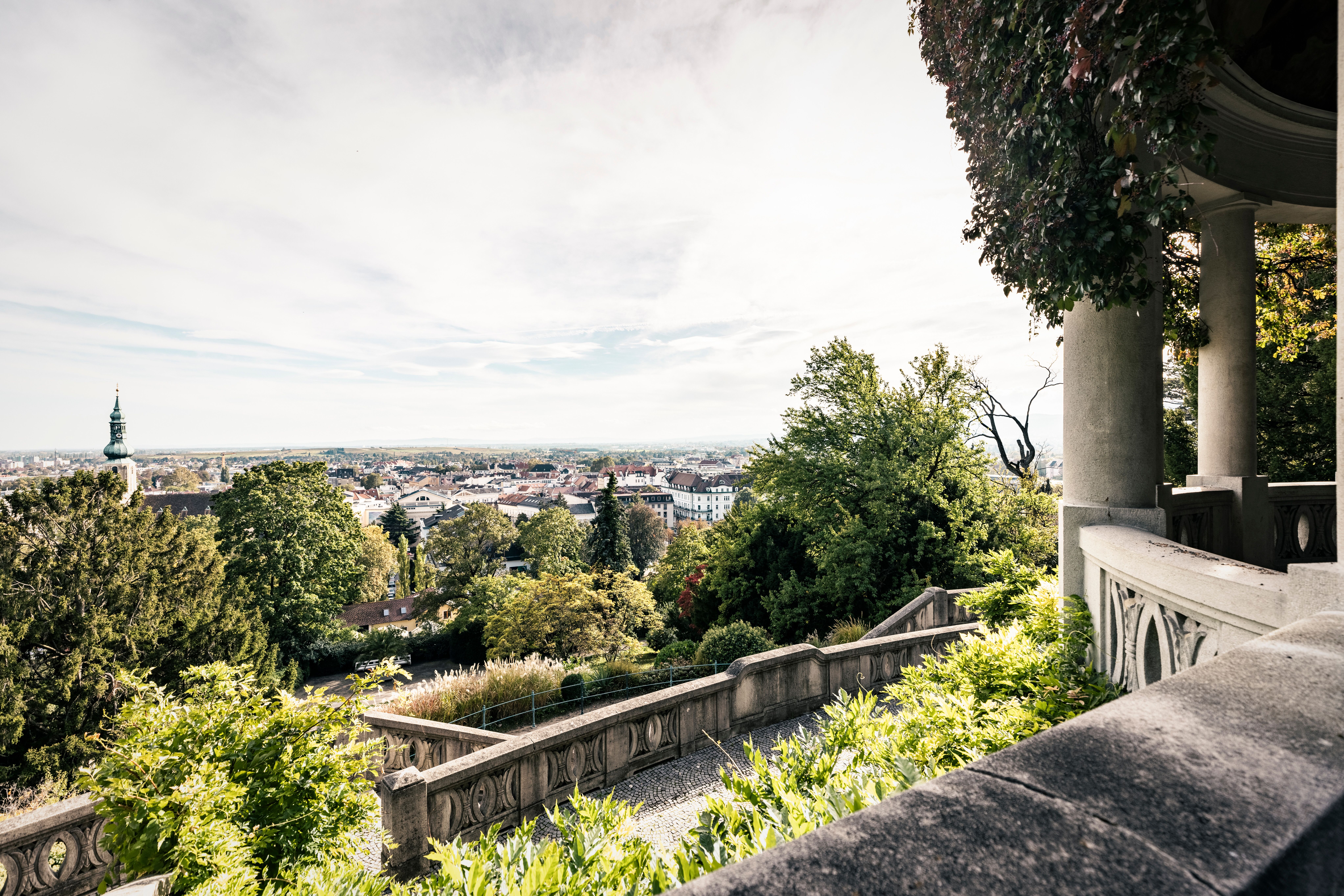 Die sanften Hügel und üppigen Bäume umarmen die Stadt, während die Sonne sanft über die Dächer strahlt. Ein atemberaubender Blick auf die malerische Landschaft lädt dazu ein, die frische Bergluft zu genießen und die Ruhe der Natur zu erleben.