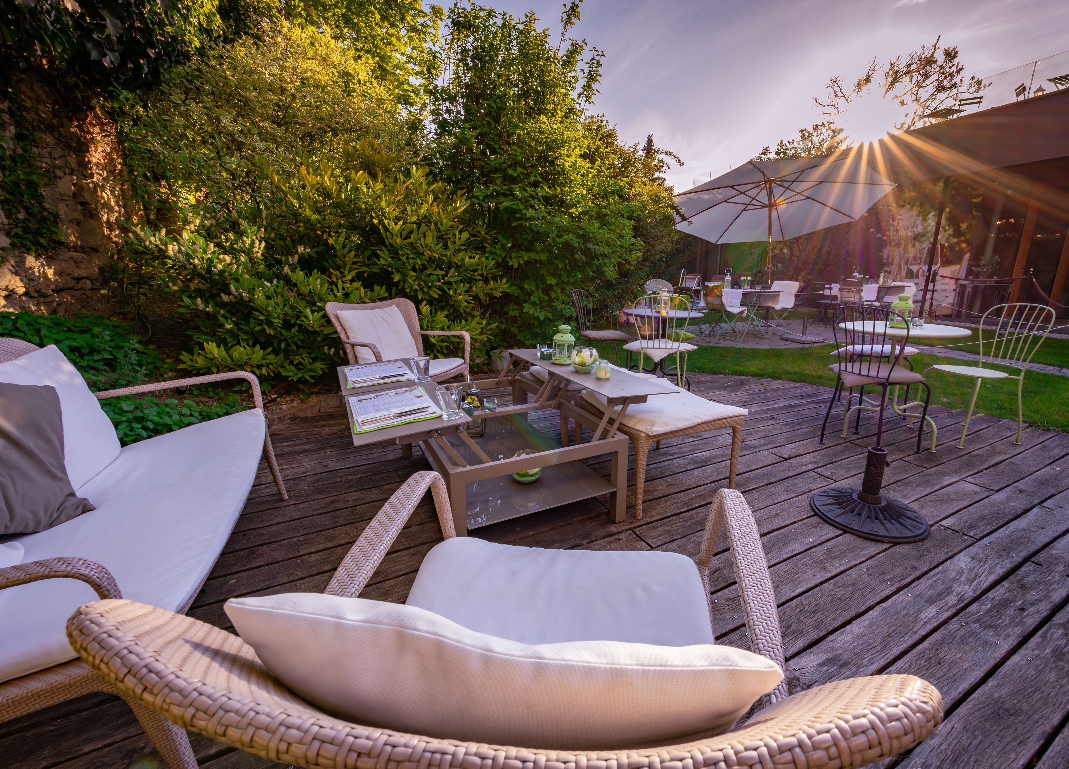 Gemütliche Terrasse mit Sitzmöbeln und Sonnenschirmen im Garten eines Hotels.