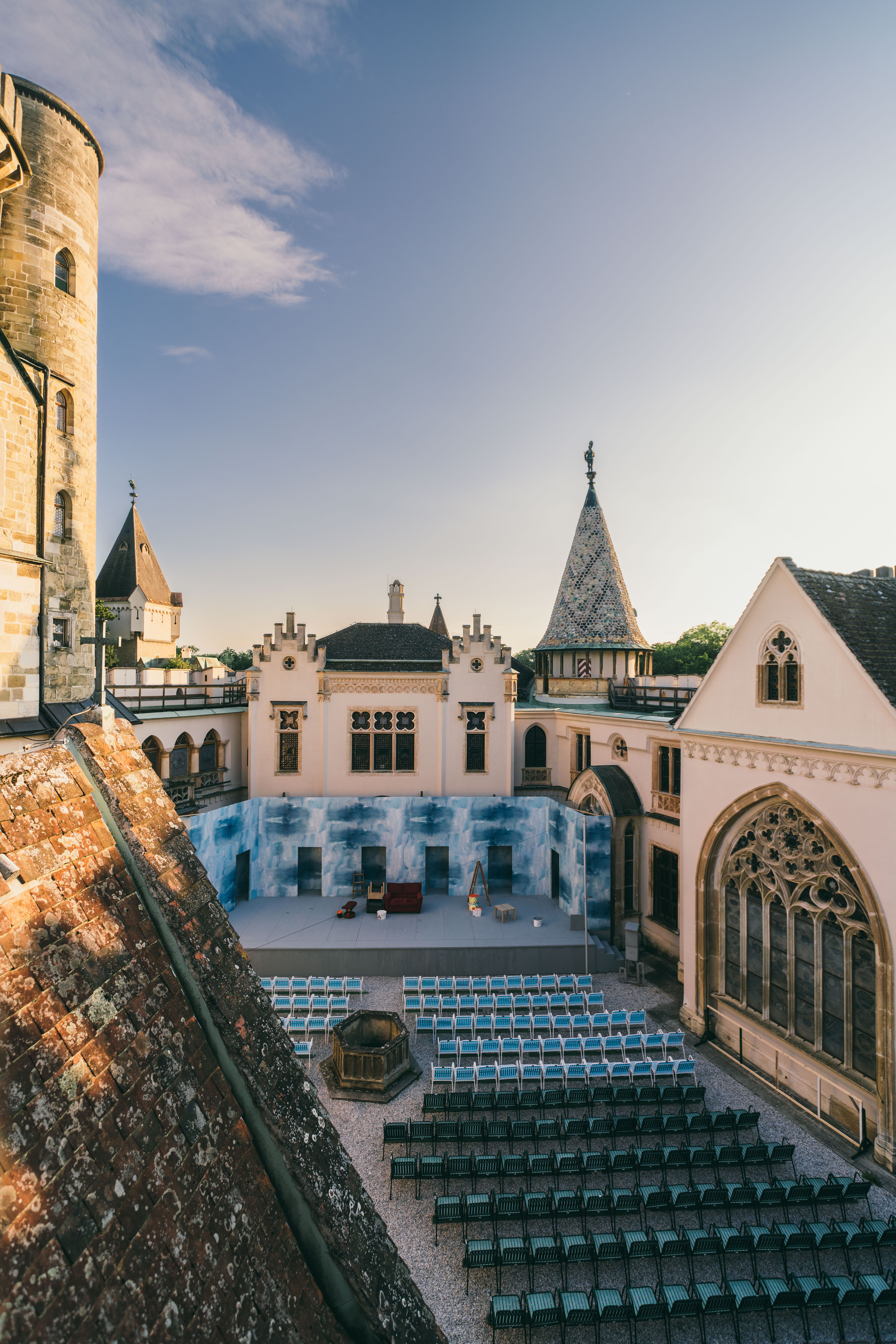 In der malerischen Kulisse des Festivallands entfaltet sich eine zauberhafte Atmosphäre, während die Stühle auf dem Platz auf die kommenden Darbietungen warten. Die historischen Gebäude umrahmen die Bühne und laden Besucher ein, in eine Welt voller Kunst und Kultur einzutauchen.
