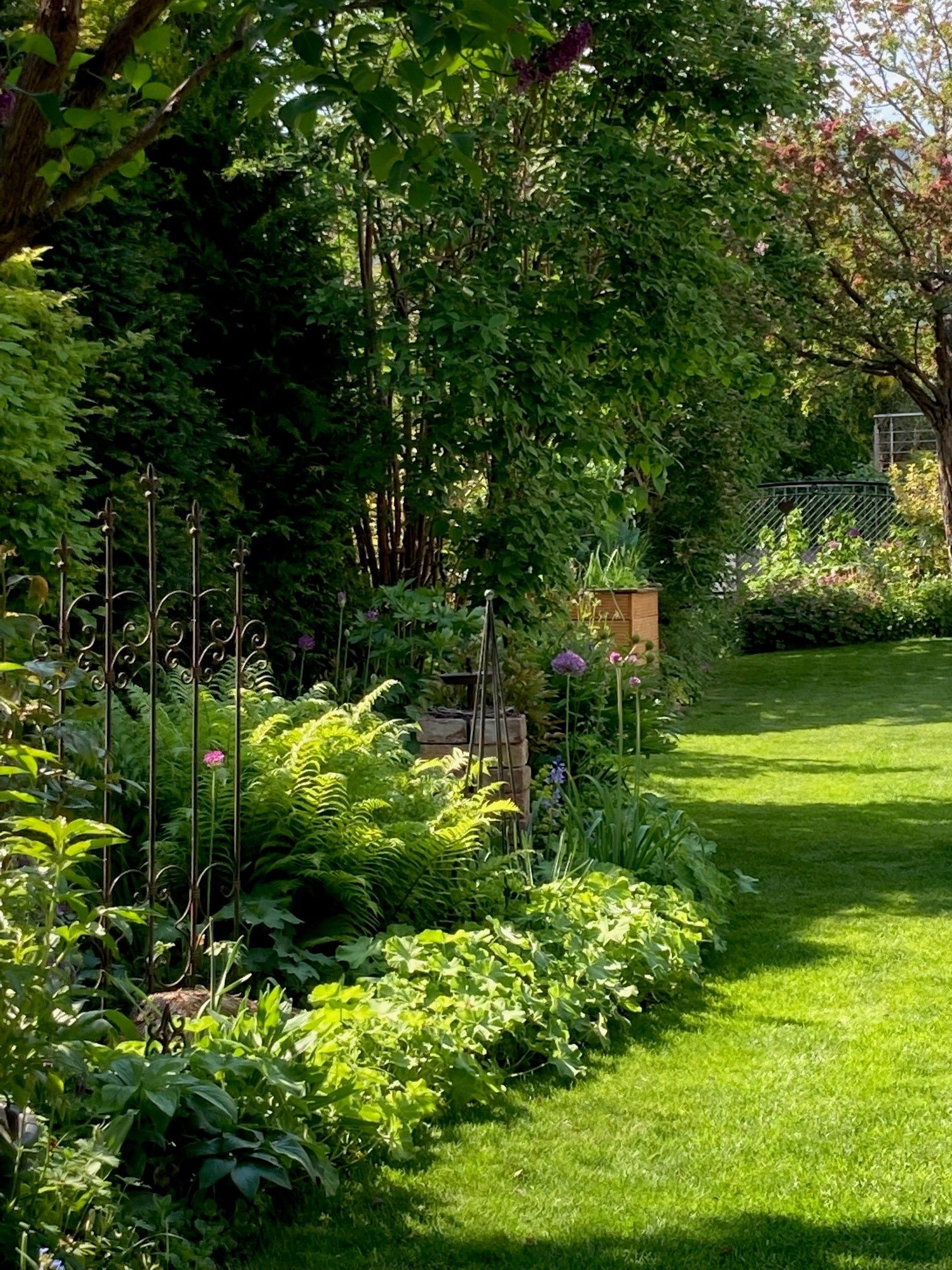 Ein gepflegter Garten mit üppigem Grün, Blumen und einem kleinen Zaun.