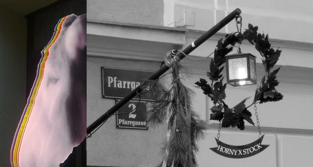 Ein Eselskopf mit bunten Streifen neben einem Straßenschild und einer Laterne mit Kranz.