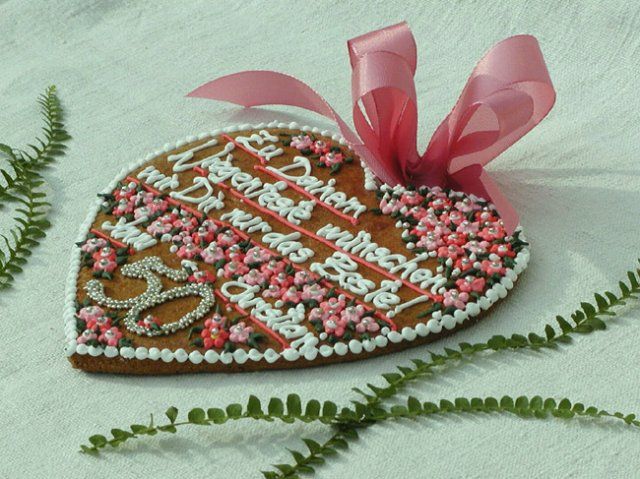 Herzförmiges Lebkuchenherz mit rosa Schleife und Verzierung.