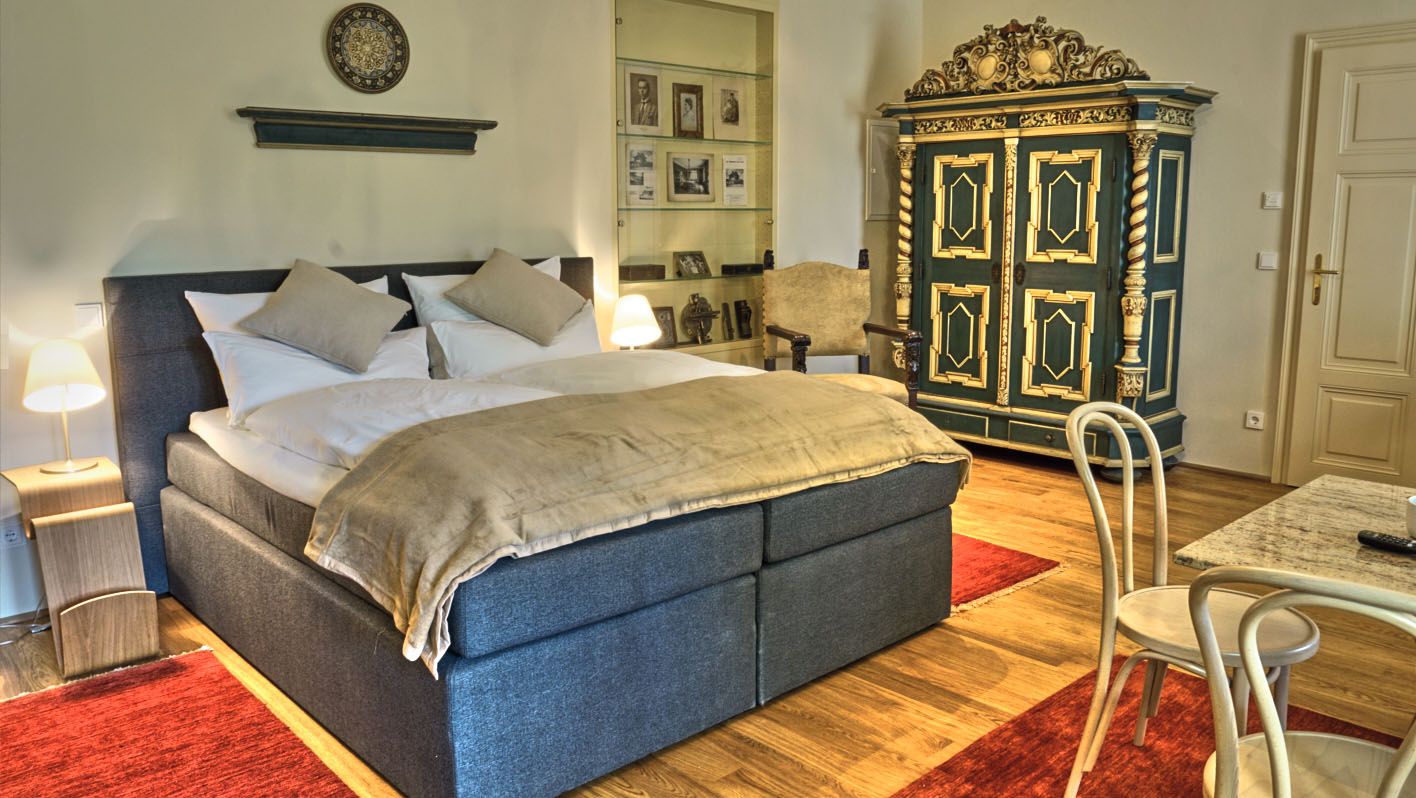 Elegantes Schlafzimmer mit Doppelbett, antikem Schrank und roten Teppichen.