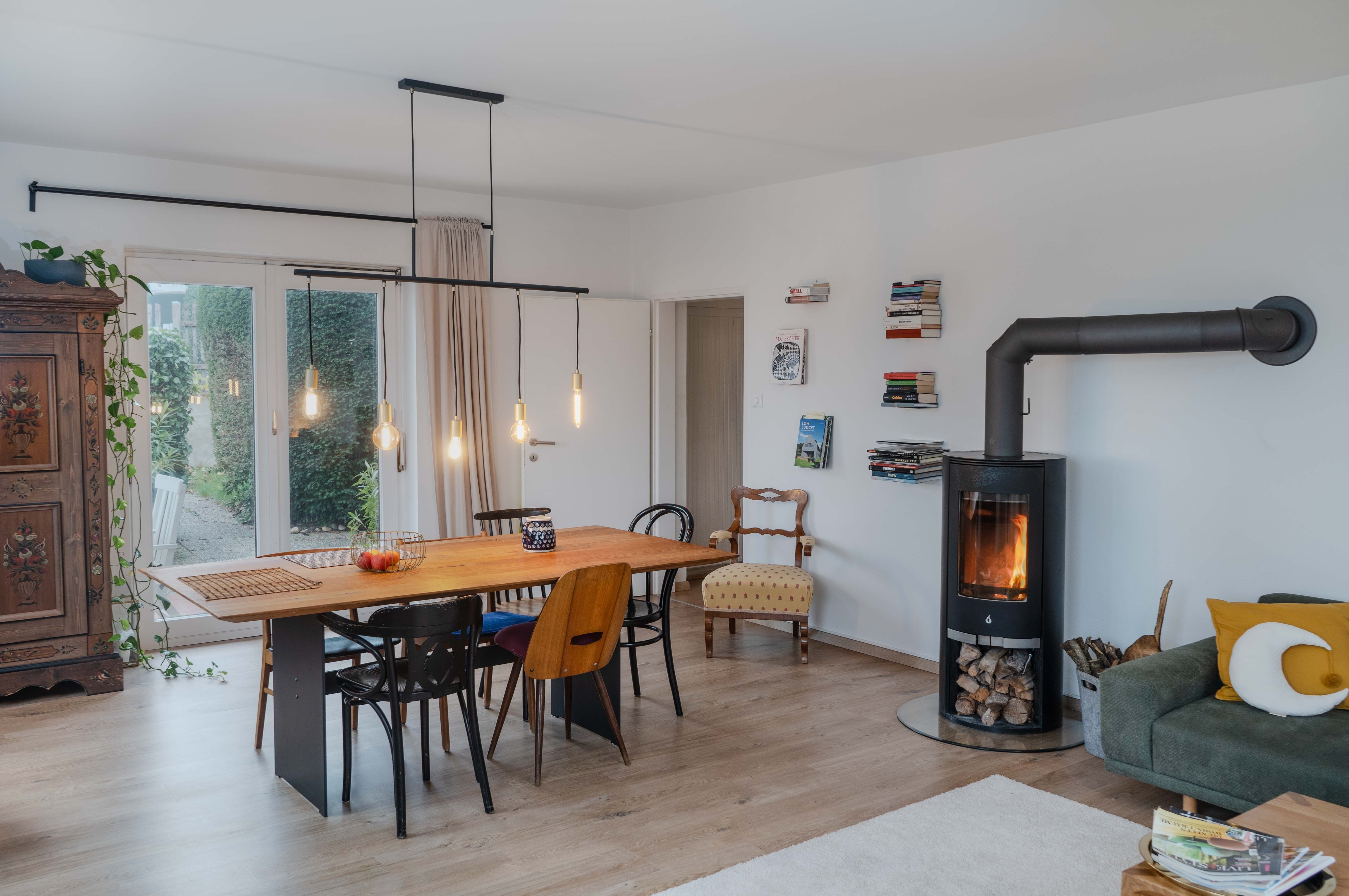 Modernes Wohnzimmer mit Esstisch, Stühlen, Kamin und Bücherregalen.