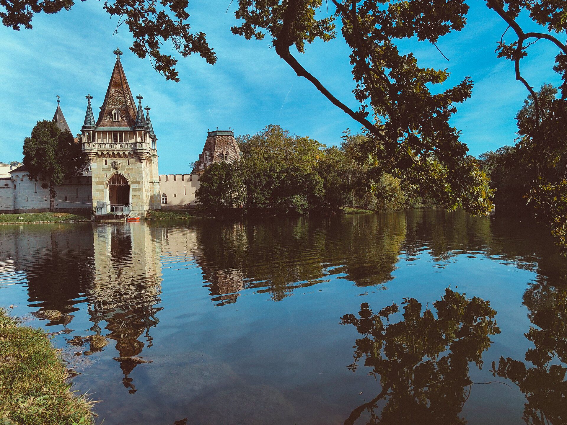 Die majestätische Franzensburg spiegelt sich im ruhigen Wasser des Teiches wider, umgeben von üppigem Grün und sanften Hügeln. Hier, wo Geschichte und Natur harmonisch verschmelzen, lädt die malerische Kulisse zu einem entspannten Spaziergang ein.