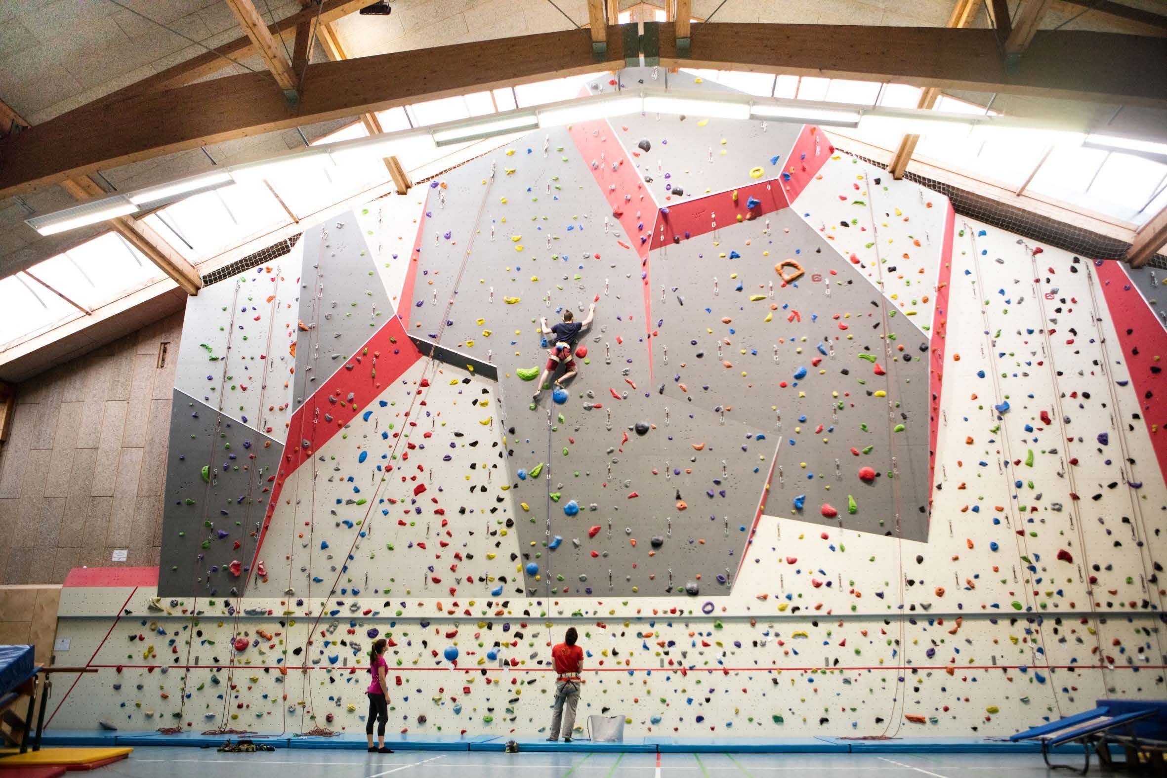 Kletterhalle mit Kletterwand und Personen beim Klettern.