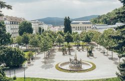 Der Kurpark lädt mit seinen gepflegten Grünflächen und schattenspendenden Bäumen zu einem entspannenden Spaziergang ein. Die sanfte Brise und das Plätschern des Brunnens schaffen eine harmonische Atmosphäre, die zum Verweilen einlädt.