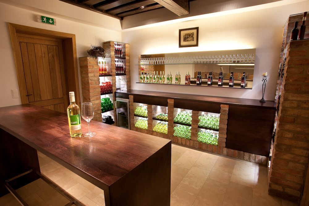 Innenansicht einer stilvollen Vinothek mit Weinflaschen und Gläsern auf Regalen.