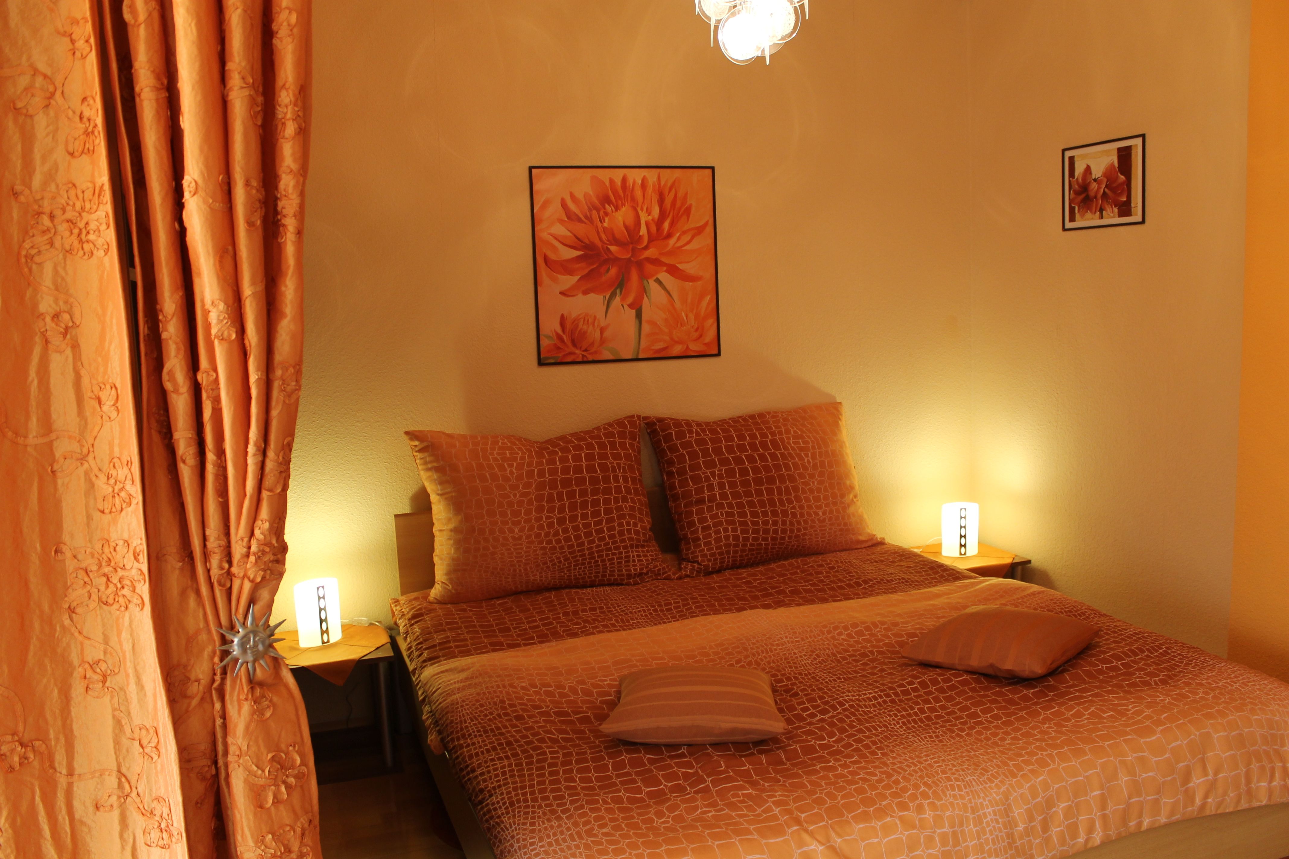 Ein gemütliches Schlafzimmer mit orangefarbener Dekoration und Beleuchtung.