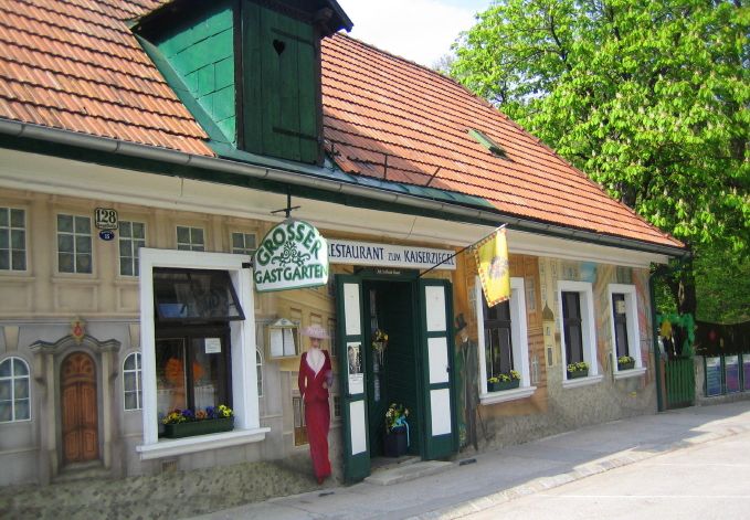 Außenansicht eines Restaurants mit bemalter Fassade und Schild 'Großer Gastgarten'.