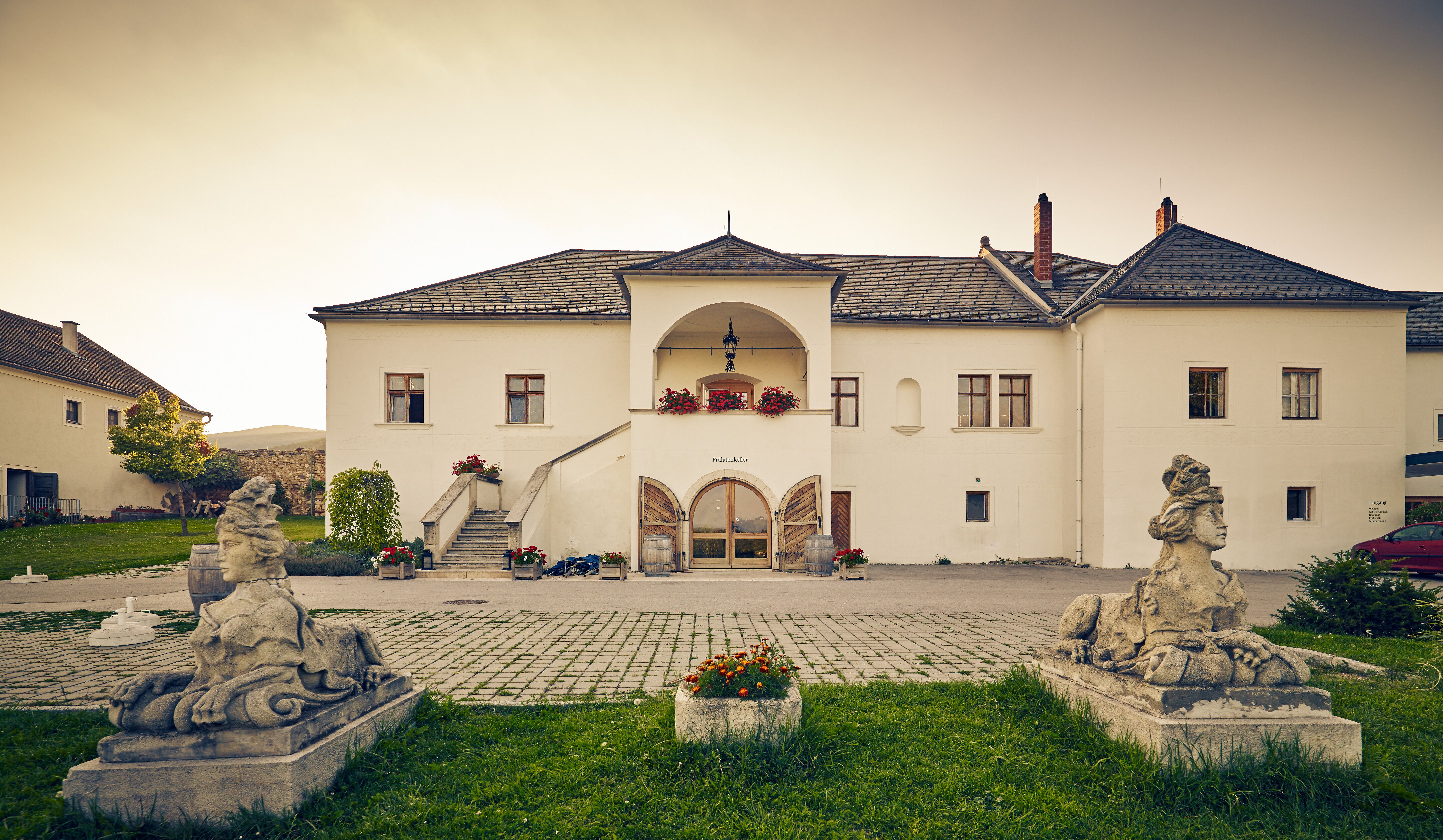 Umgeben von sanften Hügeln und üppigem Grün strahlt das Freigut Thallern eine einladende Ruhe aus. Die harmonische Architektur und die liebevoll gestalteten Blumenbeete laden dazu ein, die Seele baumeln zu lassen und die Schönheit der Natur zu genießen.