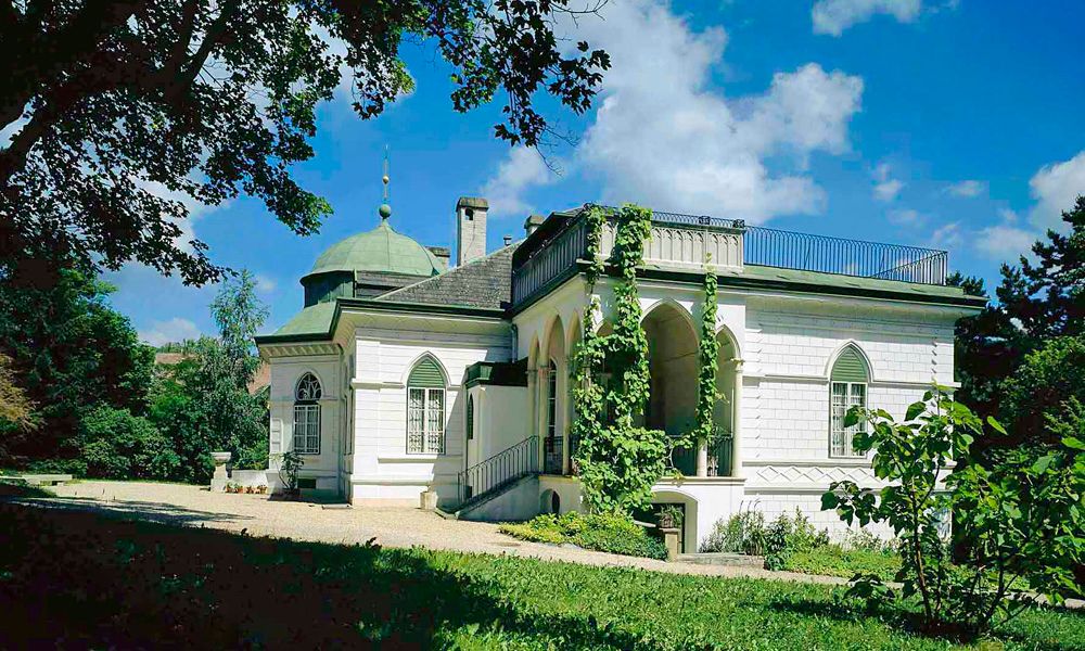 Das Geymüllerschlössel in einem grünen Garten bei sonnigem Wetter.