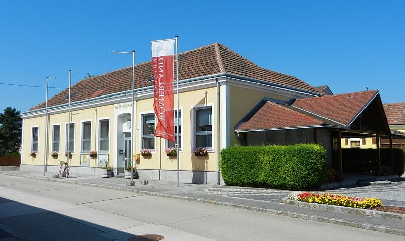 Gemeindeamt in Rauchenwarth, gelbes Gebäude mit rotem Dach und Blumen.