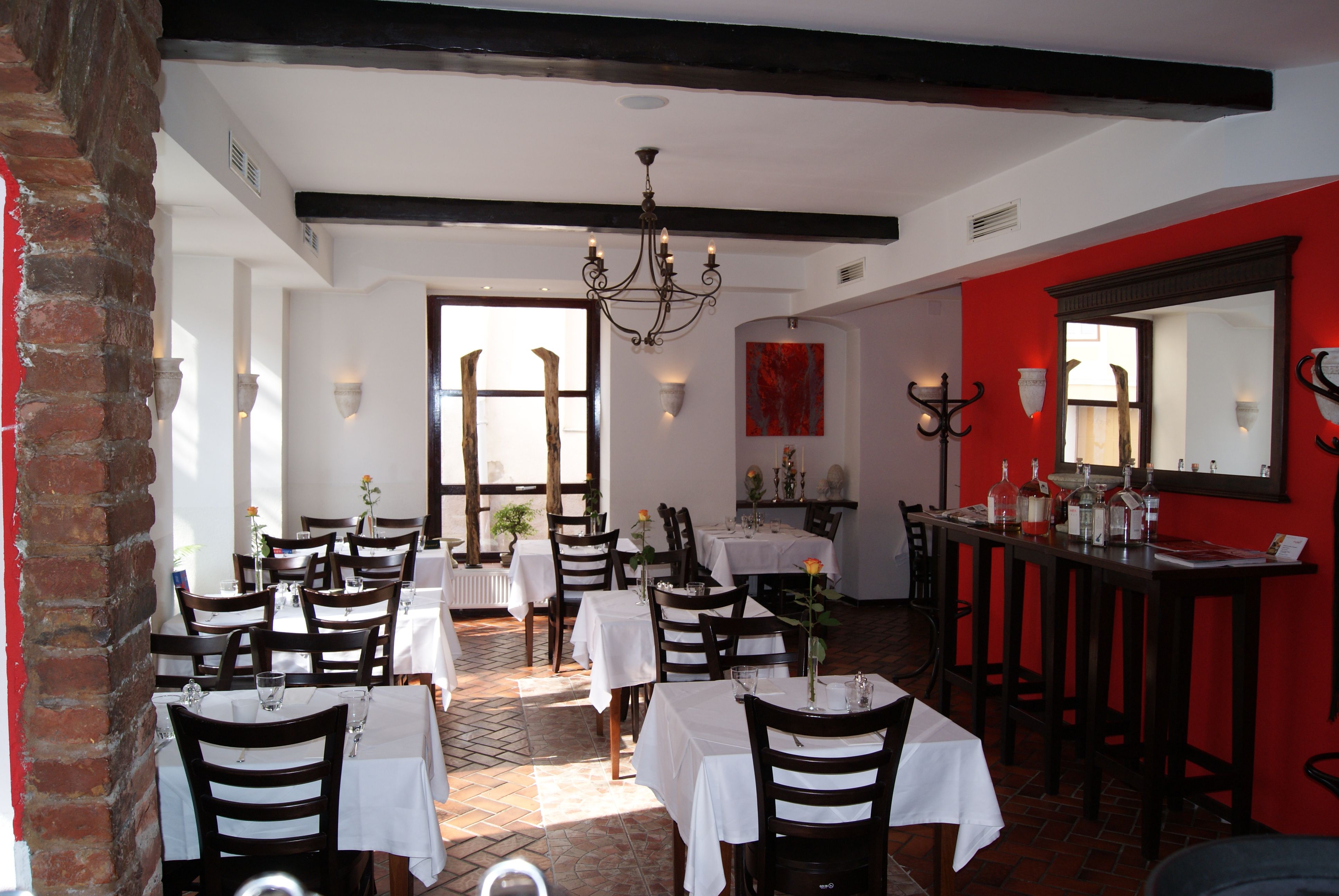 Innenansicht eines stilvollen Restaurants mit weißen Tischdecken und dunklen Holzmöbeln.