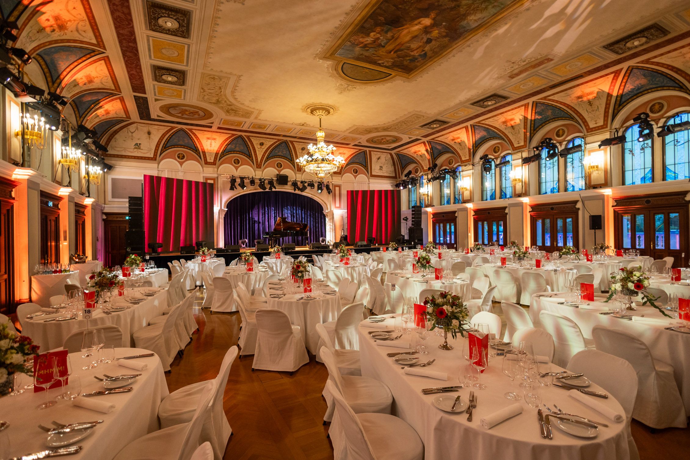 Eleganter Festsaal mit gedeckten Tischen und Bühne im Congress Center Baden.