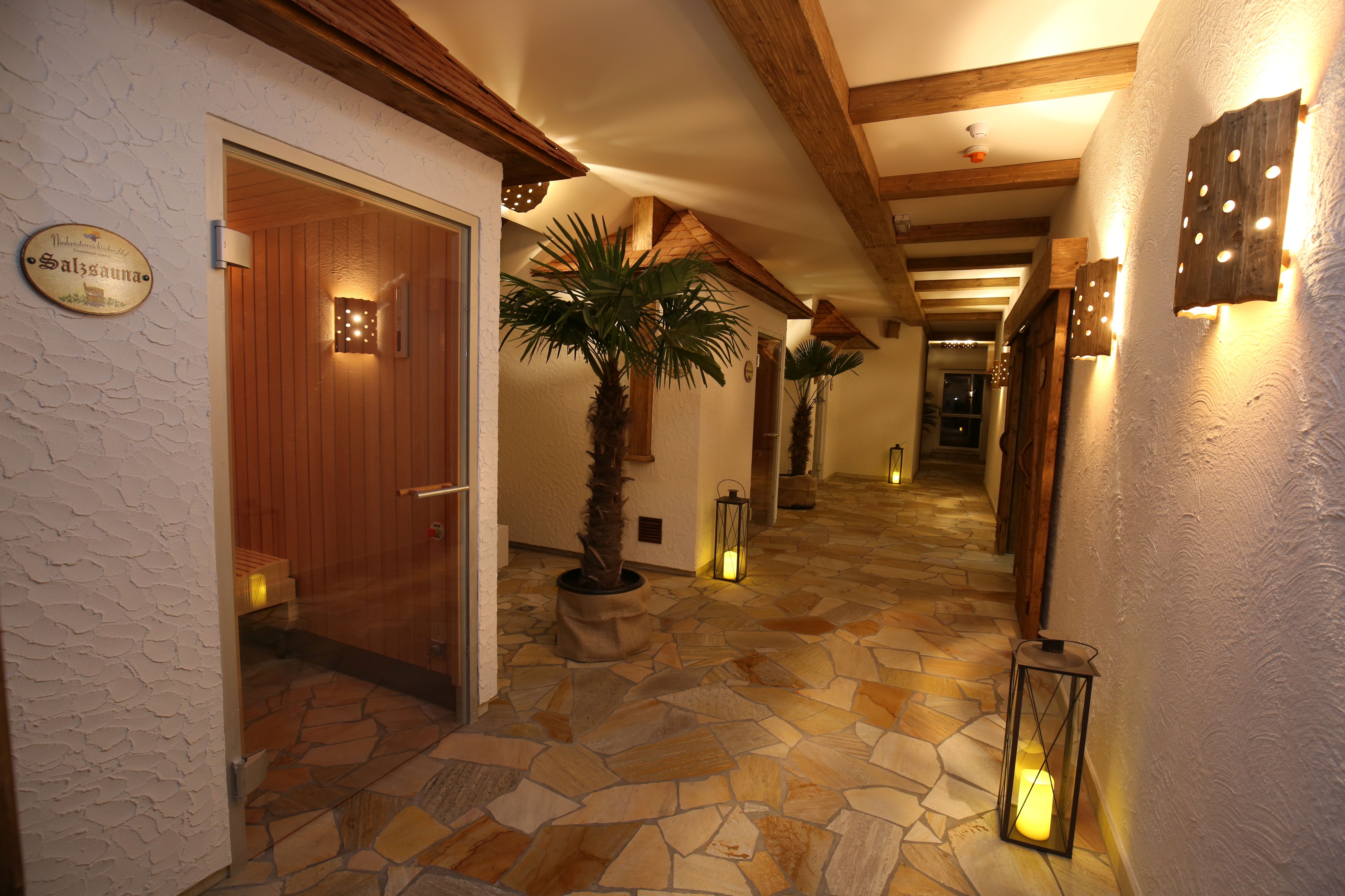 Ein Spa-Flur mit Salzsauna, Palmen, Laternen und Holzelementen.