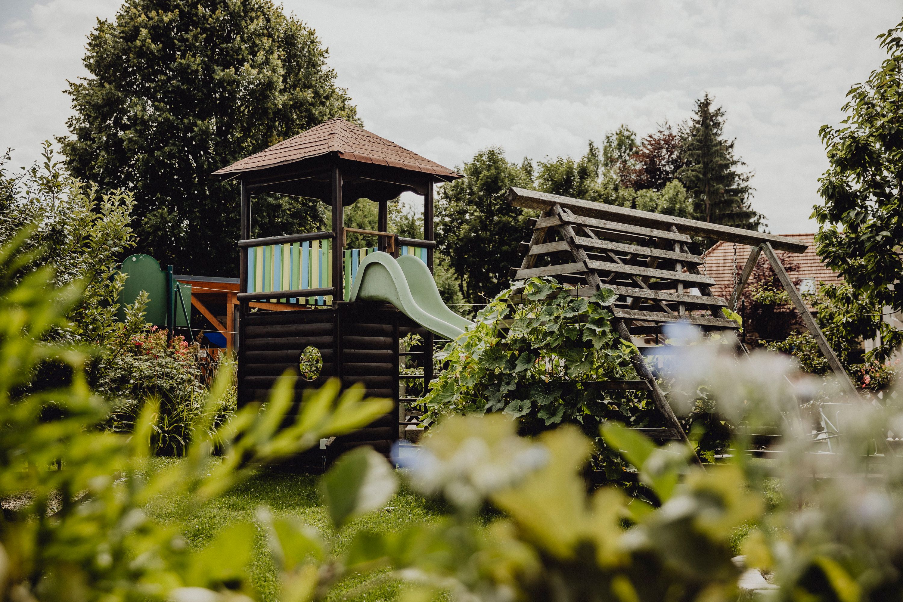Ein Spielplatz mit Rutsche und Klettergerüst in einem grünen Garten.