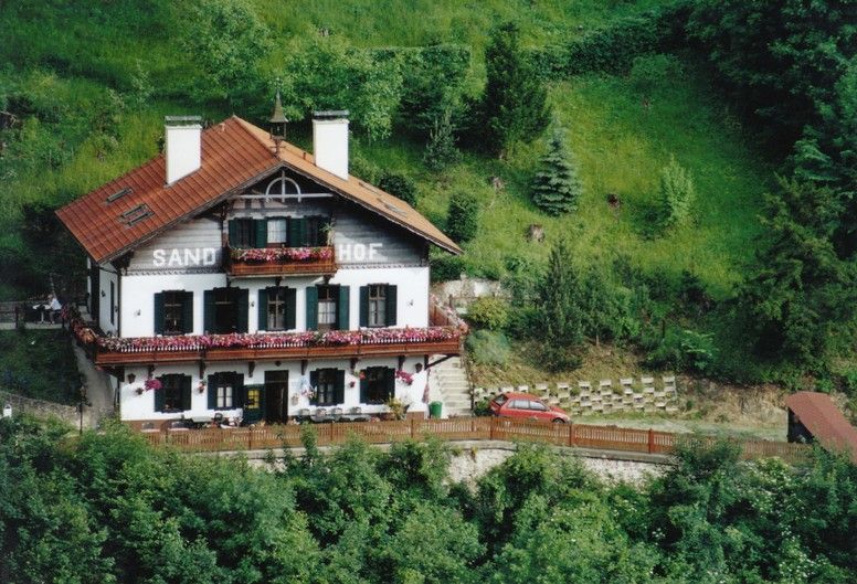 Traditionelles Haus namens Sand-Hof in grüner Landschaft.
