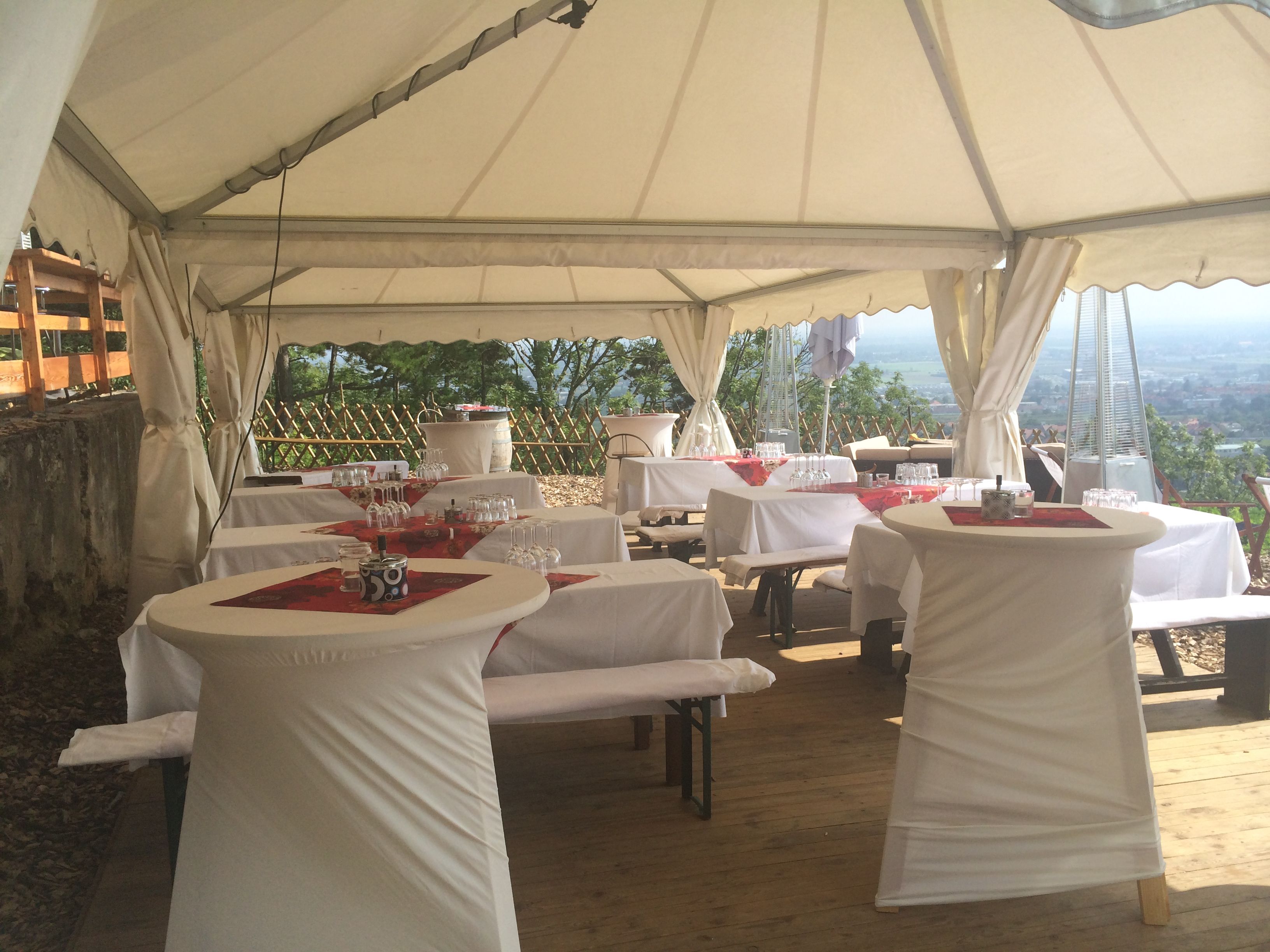 Festzelt mit gedeckten Tischen und Stehtischen, dekoriert für eine Feier.