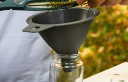 Inmitten der grünen Pracht des Wienerwaldes wird frisches Nadelgrün sorgfältig in ein Glas gefüllt. Die sanften Klänge der Natur umgeben die Szene und laden dazu ein, die Aromen des Waldes zu genießen. Ein Moment der Ruhe und des Genusses, der die Sinne belebt.