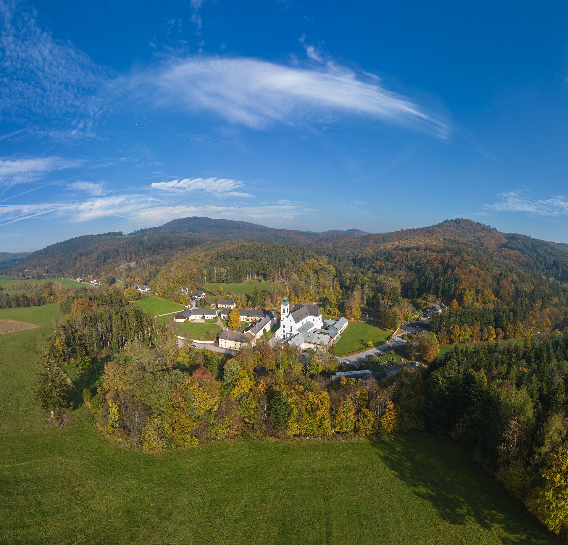Drohnenaufnahme der Basilika Klein-Mariazell in Altenmarkt an der Triesting im oberen Triestingtal; barockisierte Wallfahrtskirche eingebettet in herbstlich gefärbte, waldreiche Landschaft des Wienerwalds bei Sonnenschein.