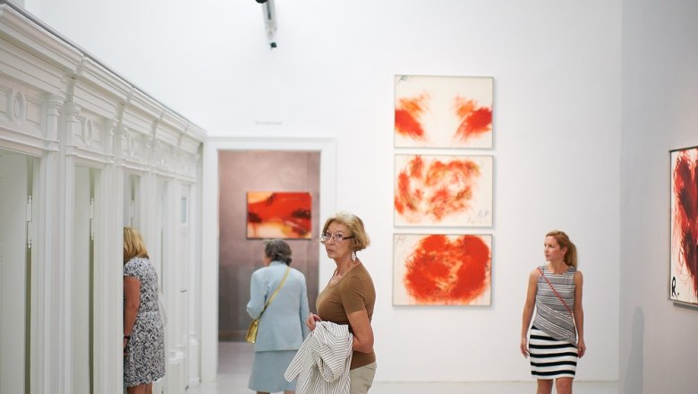 Besucher im Arnulf Rainer Museum betrachten Kunstwerke an weißen Wänden.